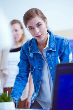 Masanın yanında duran iki genç kadın enstrüman, plan ve dizüstü bilgisayarla.