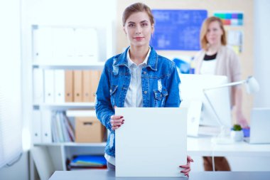 Masanın yanında duran iki genç kadın enstrüman, plan ve dizüstü bilgisayarla.