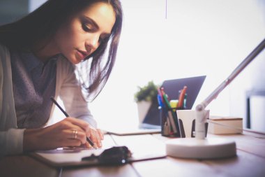 Masada oturan genç bir bayan. İş kadınıyım. Çizim. Öğrenci. İş yeri. Masa.
