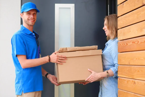 Leende leverans man i blå uniform leverera paket låda till mottagaren - kurir service koncept. Leende leverans man i blå uniform — Stockfoto