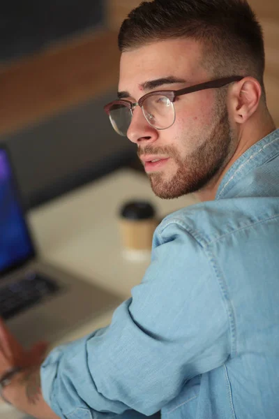 Jonge man met behulp van een telefoon en werken op een laptop. Student SMS op de telefoon. — Stockfoto