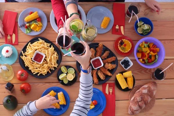 Vista superior do grupo de pessoas que jantam juntas enquanto estão sentadas à mesa de madeira. Comida na mesa. As pessoas comem fast food. — Fotografia de Stock