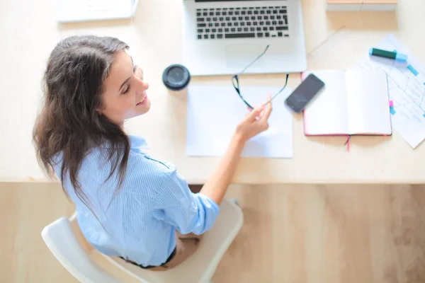 Giovane donna seduta al tavolo dell'ufficio, guardando lo schermo del computer portatile. Giovane donna — Foto Stock