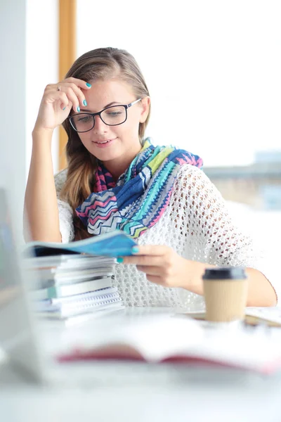 Giovane donna seduta ad una scrivania tra i libri. Studente — Foto Stock