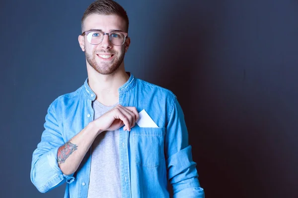 Joven sosteniendo una tarjeta de crédito de pie sobre fondo gris. Joven empresario. —  Fotos de Stock