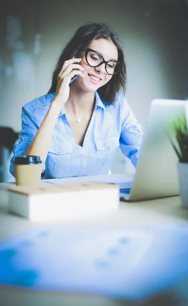 美しい若いビジネスマンの女性がオフィスの机に座って携帯電話で話しています。実業家 — ストック写真