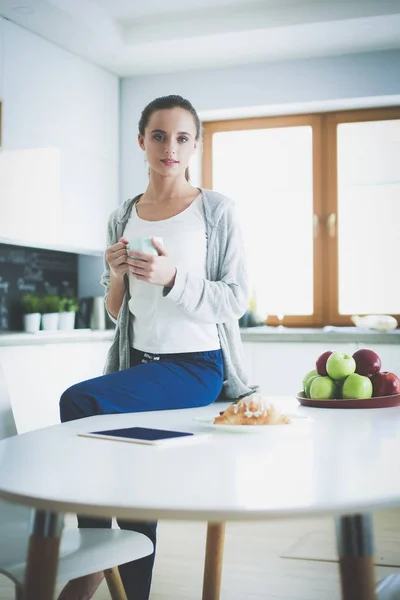 Szczęśliwa kobieta picia herbaty w kuchni w domu. — Zdjęcie stockowe