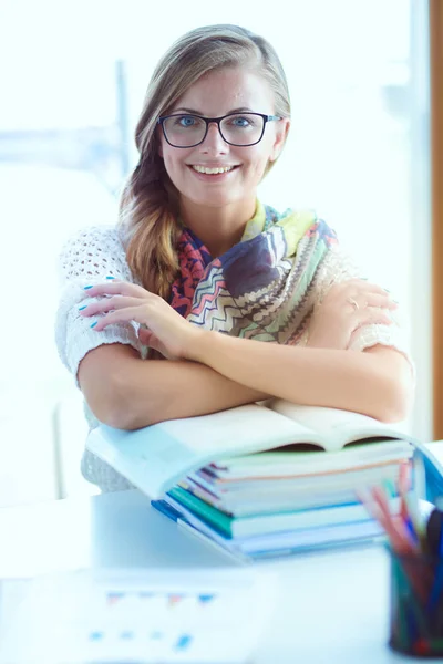 Młoda kobieta siedząca za biurkiem wśród książek. Student — Zdjęcie stockowe