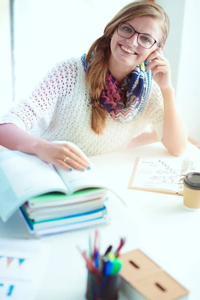 本の間の机に座っている若い女性。学生 — ストック写真