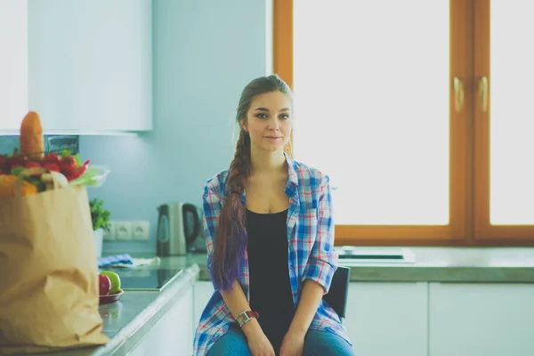 Портрет молодой женщины, стоящей со скрещенными руками на фоне кухни. — стоковое фото