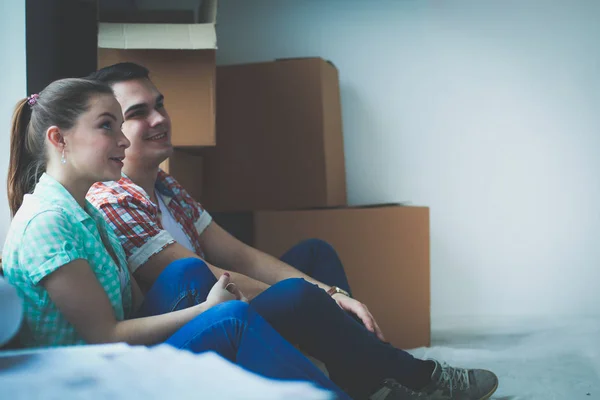 Couple moving in house sitting on the floor. Couple