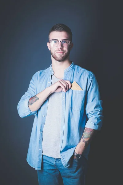 Young man holding a credit card standing on gray background. Young entrepreneur. — Stock Photo, Image