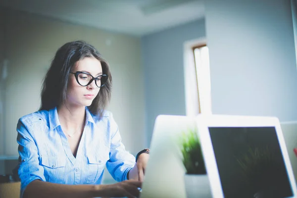 Jovem mulher sentada na mesa do escritório, olhando para a tela do computador portátil. Jovem mulher — Fotografia de Stock