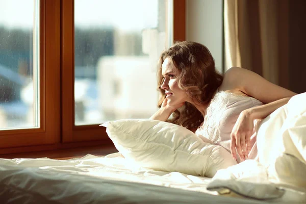 Vrouw in bed te liggen op de vroege ochtend in de buurt van venster. — Stockfoto
