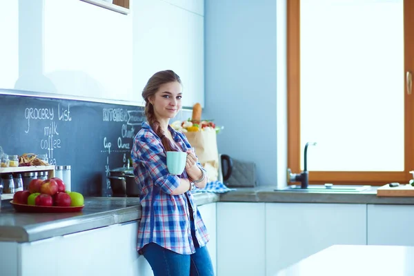 Szczęśliwa kobieta picia herbaty w kuchni w domu. — Zdjęcie stockowe