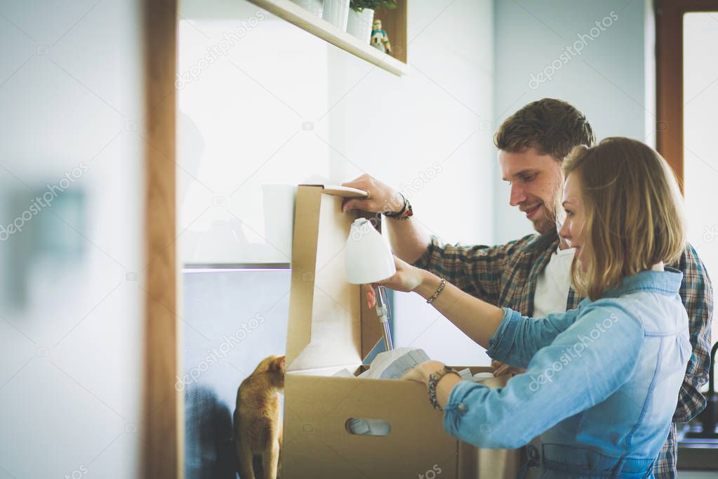 Young couple carrying big cardboard box at new home.Moving house. Young couple