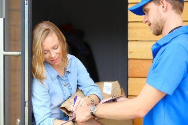 Mavi üniformalı gülümseyen kurye servis konseptine paket kutusu teslim eden teslimatçı. Mavi üniformalı gülümseyen teslimatçı.