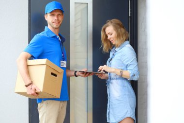 Mavi üniformalı gülümseyen kurye servis konseptine paket kutusu teslim eden teslimatçı. Mavi üniformalı gülümseyen teslimatçı.