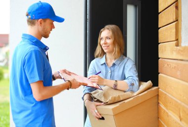 Mavi üniformalı gülümseyen kurye servis konseptine paket kutusu teslim eden teslimatçı. Mavi üniformalı gülümseyen teslimatçı.