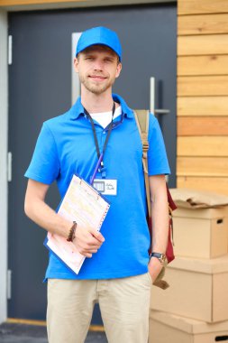 Mavi üniformalı gülümseyen kurye servis konseptine paket kutusu teslim eden teslimatçı. Mavi üniformalı gülümseyen teslimatçı.