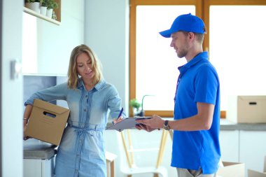 Mavi üniformalı gülümseyen kurye servis konseptine paket kutusu teslim eden teslimatçı. Mavi üniformalı gülümseyen teslimatçı.