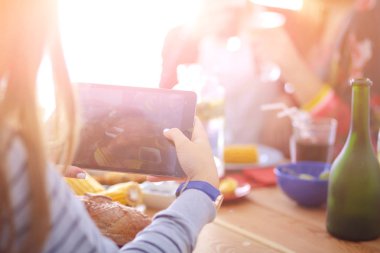 Ahşap masada otururken birlikte yemek yiyen bir grup insanın üst düzey görüntüsü. Masada yemek var. İnsanlar fast food yiyor..