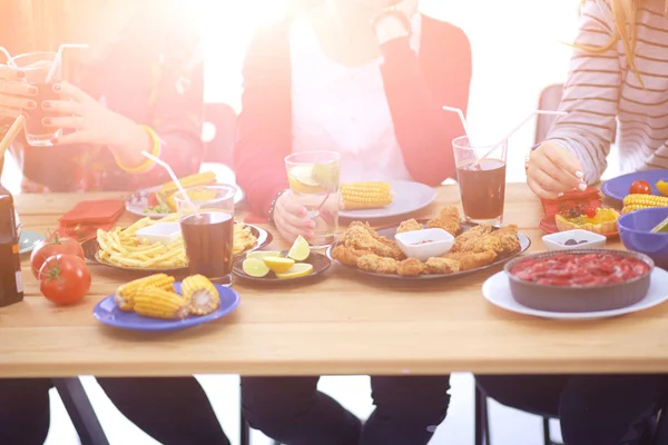 Vista superior do grupo de pessoas que jantam juntas enquanto estão sentadas à mesa de madeira. Comida na mesa. As pessoas comem fast food. — Fotografia de Stock