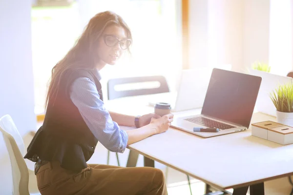 Молодая женщина сидит за рабочим столом с ноутбуком. Молодая женщина. Ноутбук — стоковое фото