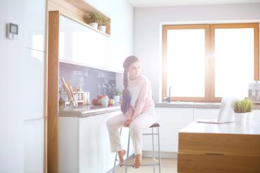 Mutfakta masada oturan genç kadın.