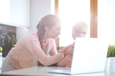 Annesi bebeğini evde parlak mutfakta ile.