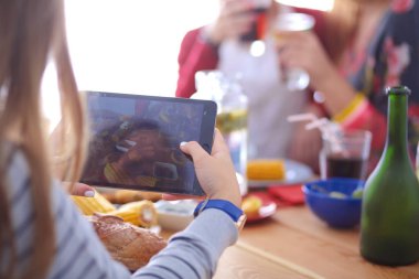 Ahşap masada otururken birlikte yemek yiyen bir grup insanın üst düzey görüntüsü. Masada yemek var. İnsanlar fast food yiyor..