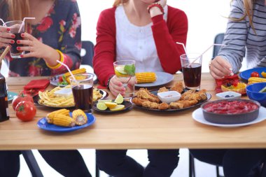Ahşap masada otururken birlikte yemek yiyen bir grup insanın üst düzey görüntüsü. Masada yemek var. İnsanlar fast food yiyor..