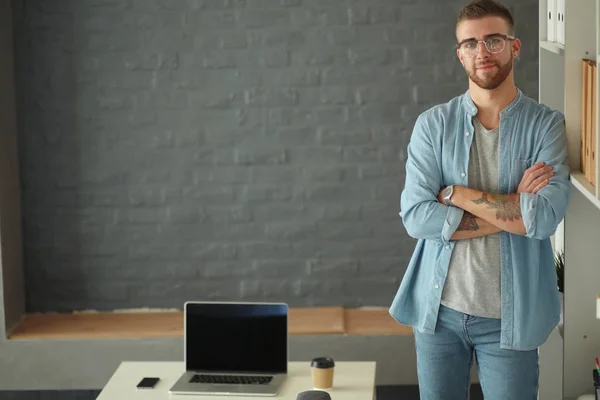 Young man holding laptop standing near wall. — Stock Photo, Image