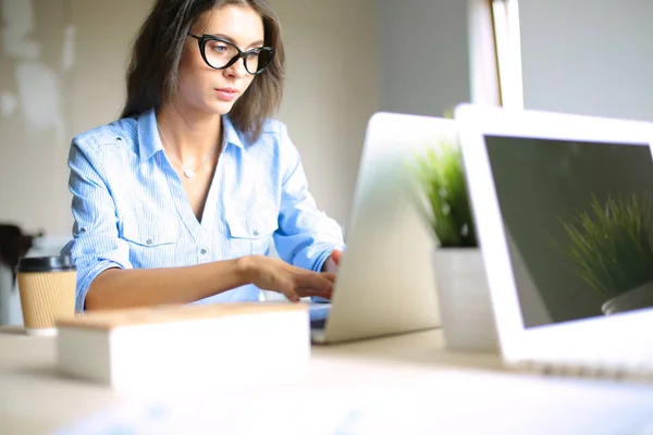 Mujer joven sentada en la mesa de la oficina, mirando la pantalla del ordenador portátil. Mujer joven — Foto de Stock