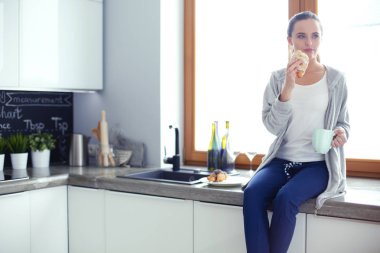 Mutfakta dijital tablet kullanan güzel genç bir kadın..