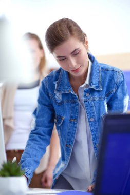 Masanın yanında duran iki genç kadın enstrüman, plan ve dizüstü bilgisayarla.