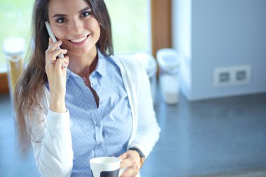 evde Mutfakta çay içme ve telefonda konuşurken mutlu kadın. Kadın mutfakta.