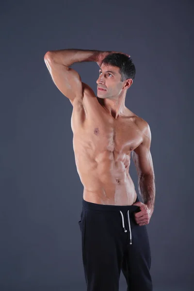 Μυώδης άνδρας. Μυώδης άνδρας σε ένα γκρίζο φόντο δείχνει τους μυς. Εκπαιδευτή γυμναστικής. Επαγγελματικής ικανότητας. Προπόνηση. Ανδρικά fitness. — Φωτογραφία Αρχείου