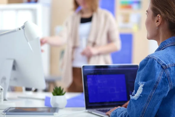 Duas jovens sentadas perto da mesa com instrumentos, plano e laptop. — Fotografia de Stock