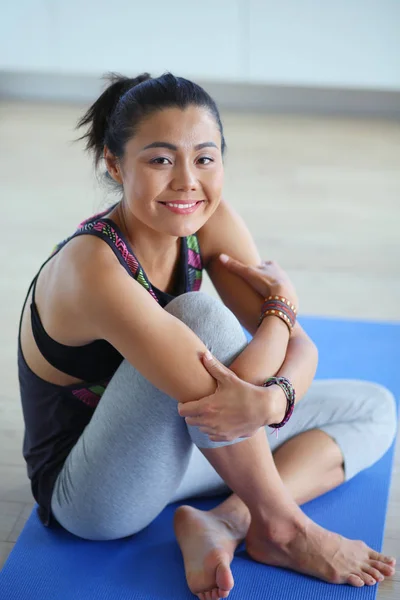 Portrait of smiling yoga woman sitting at yoga mat after workout at yoga studio. Yoga. Woman. — Stock Photo, Image