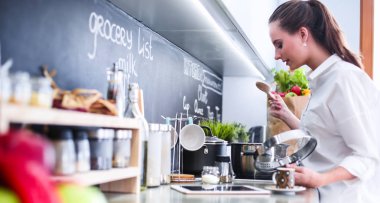 Mutfakta sobanın yanında duran genç bir kadın.