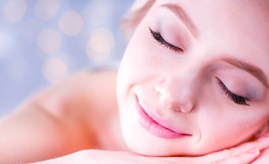 Gözleri kapalı rahatlatıcı bir masaj masanın üzerinde yatan genç kadın