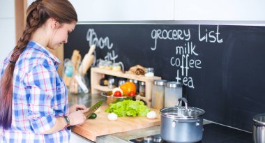 Mutfakta sobanın yanında duran genç bir kadın. .