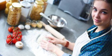 Mutfakta sobanın yanında duran genç bir kadın. .