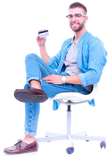 Young man sitting on chair and holding credit card — Stock Photo, Image