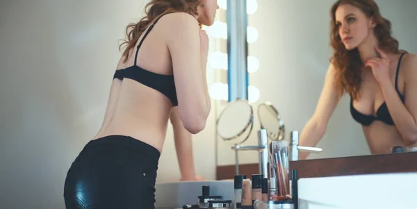 Giovane donna guardarsi allo specchio in bagno — Foto Stock