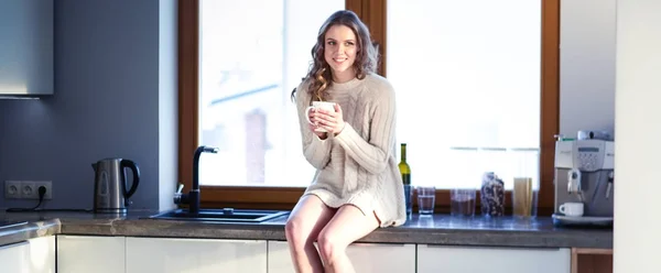 Retrato de uma mulher segurando uma xícara de chá em sua cozinha . — Fotografia de Stock