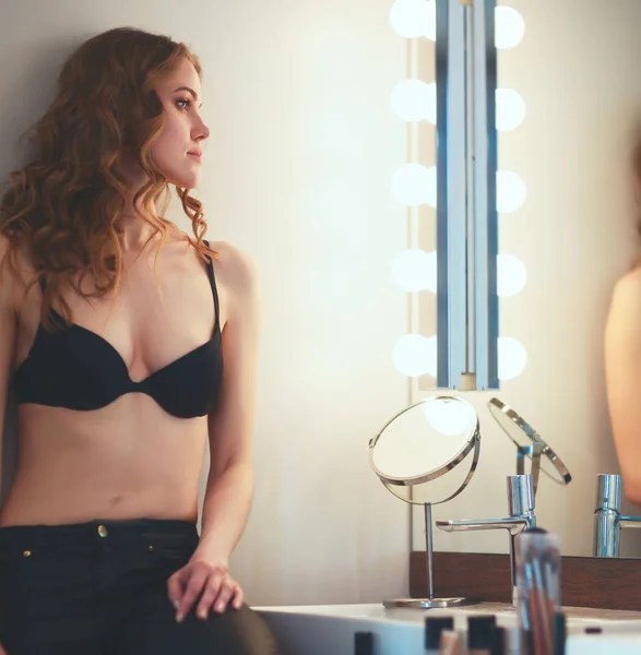 Młoda kobieta szuka siebie w lustrze w łazience — Zdjęcie stockowe