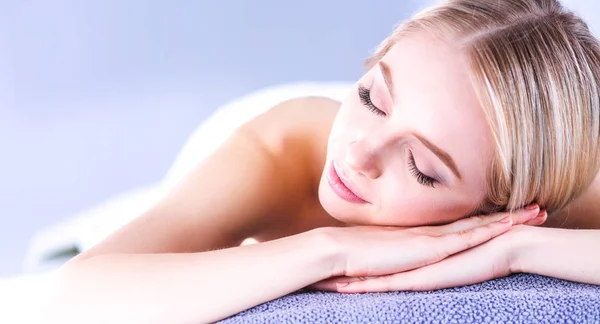 Mujer joven acostada en una mesa de masaje, relajándose con los ojos cerrados —  Fotos de Stock