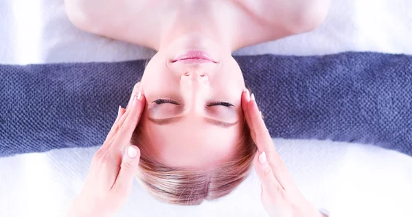 Jovem deitada em uma mesa de massagem, relaxando com os olhos fechados — Fotografia de Stock